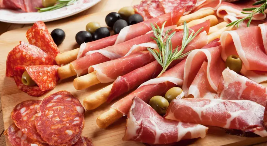 Tagliere con salumi misti, tra cui affettati non di maiale, olive e rosmarino.