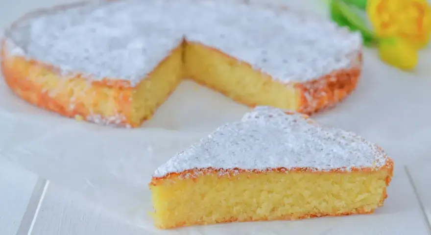 Una deliziosa torta caprese senza mandorle, spolverata di zucchero a velo, con una fetta tagliata.