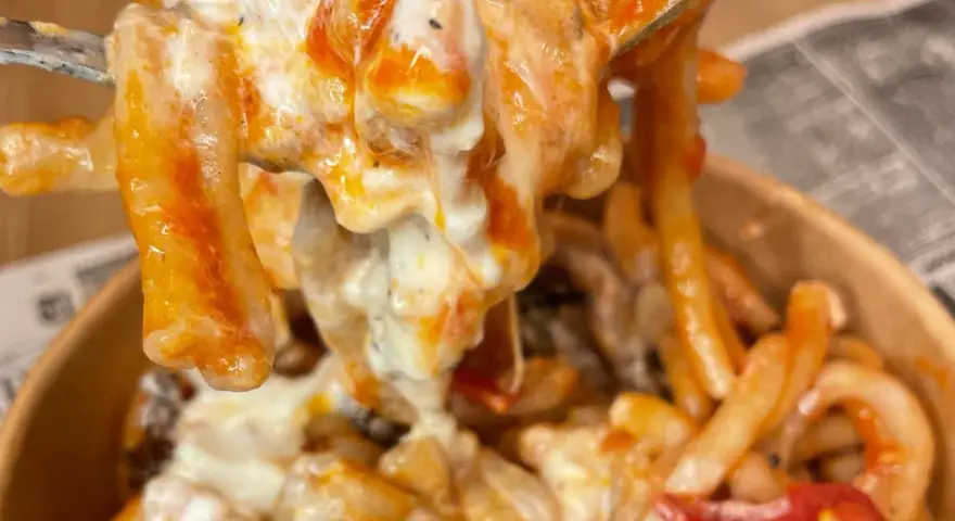 Primo piatto cremoso di pasta alla checca, con pomodoro e mozzarella filante, servito in un contenitore da asporto.