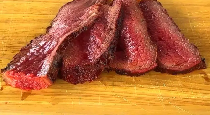 Fette succulente di spinacino di manzo, cotte alla perfezione, adagiate su un tagliere di legno.