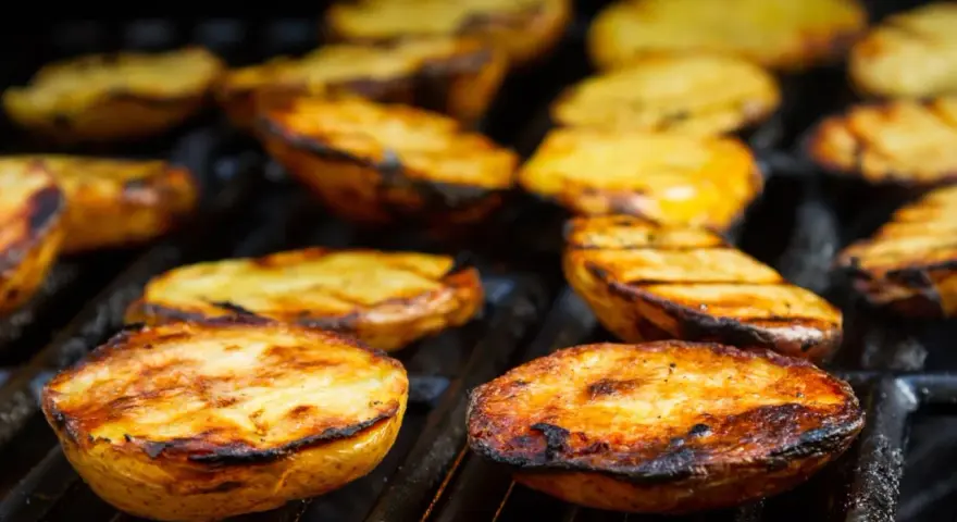 Patate alla brace dorate e succulente, con segni di grigliatura perfetti, pronte per essere gustate.