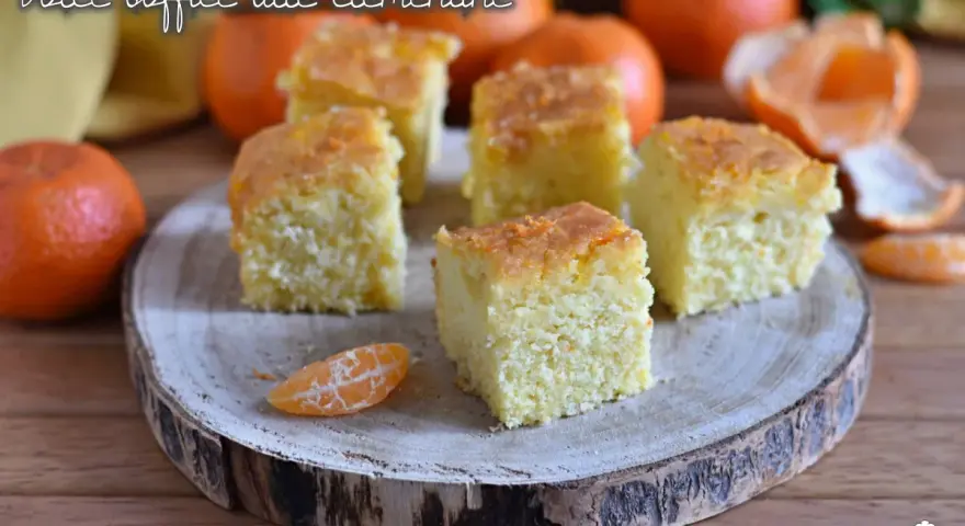 Fette di torta di clementine soffice, guarnite con scorza d'arancia, su un tagliere di legno.