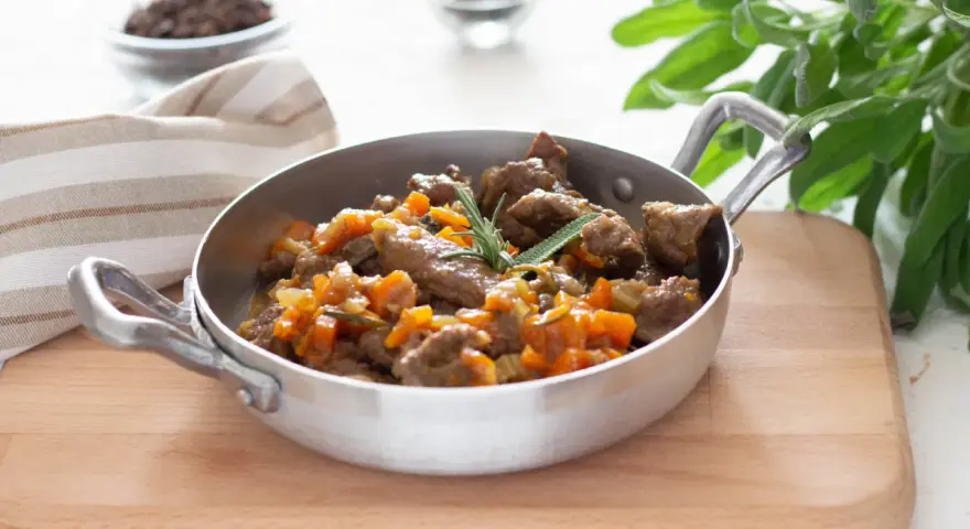 Cinghiale in umido fatto in casa da Benedetta, un piatto succulento con carne tenera e verdure, guarnito con rosmarino e salvia.