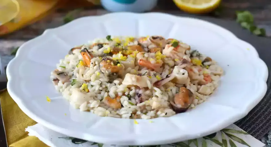 Un invitante risotto allo scoglio, ricco di cozze, gamberi e calamari, guarnito con scorza di limone.