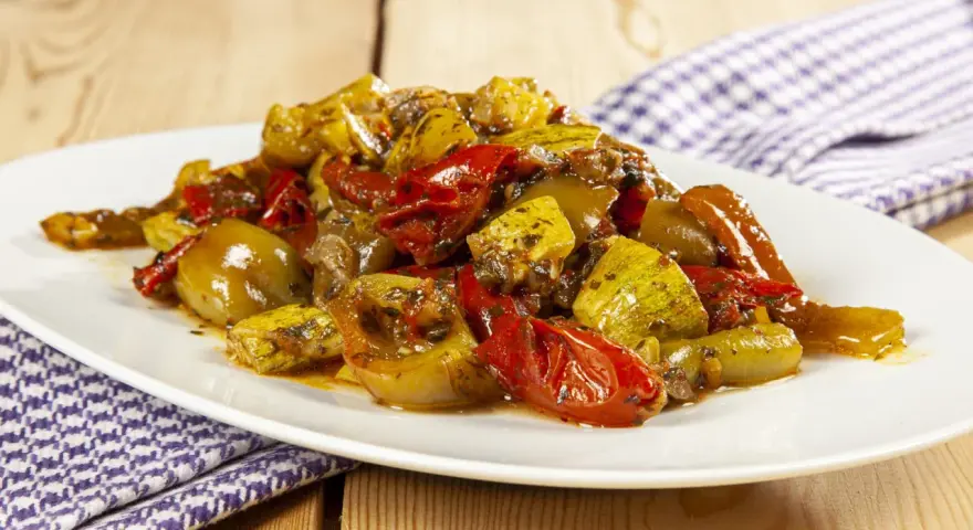 Un piatto invitante di verdure miste cotte, un'ottima gurguglione ricetta, con peperoni, zucchine e pomodori conditi con erbe aromatiche.