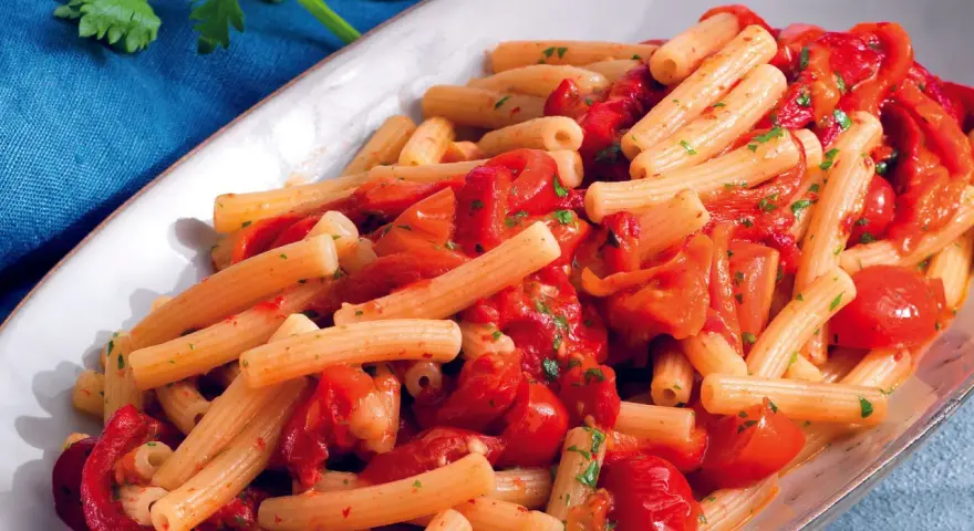 Un piatto invitante di pasta con i peperoni alla pugliese, condita con pomodoro fresco e prezzemolo.
