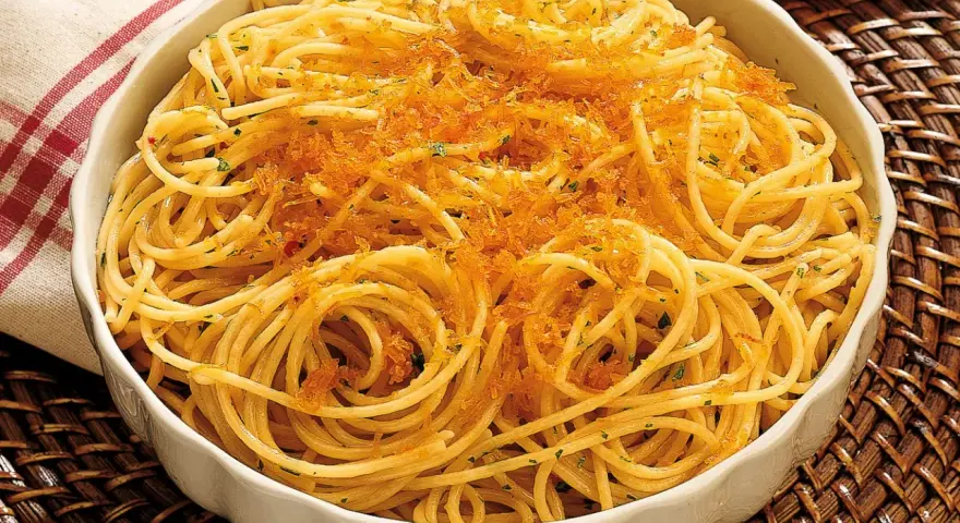 Spaghetti alla bottarga, un piatto saporito con pasta dorata e una generosa spolverata di uova di pesce essiccate.