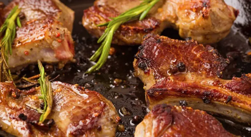Succulento agnello in padella, dorato e profumato con rosmarino e pepe.