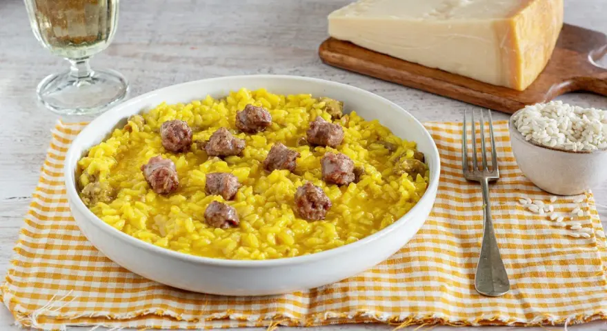 Un invitante risotto alla monzese, giallo intenso e ricco di saporiti pezzi di salsiccia, pronto per essere gustato.