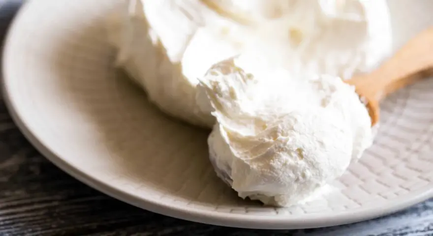 Crema bianca e soffice su un piatto, pronta per essere usata come ingredienti per mascarpone.