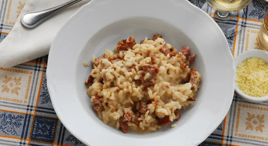 Un piatto di risotto alla pilota cremoso, con pezzetti di salsiccia, pronto per essere gustato.