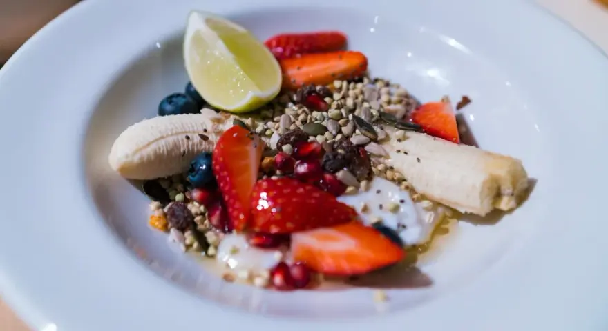 Yogurt con frutta secca, fragole, mirtilli, banana e lime. Un mix colorato e salutare per iniziare la giornata.