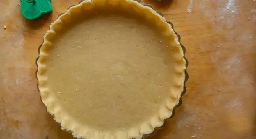 Base di pasta frolla veloce pronta per essere farcita, con bordi decorati e forata per una cottura perfetta.