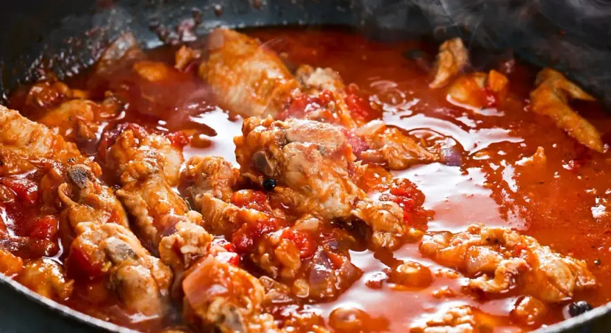 Succulenta carne alla pizzaiola che sobbolle in padella, sprigionando un invitante vapore. Pezzi di carne tenera immersi in un ricco sugo di pomodoro.