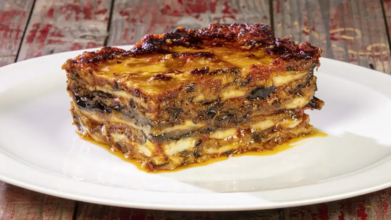Una fetta di parmigiana di melanzane, un classico delle ricette italiane, su un piatto bianco.