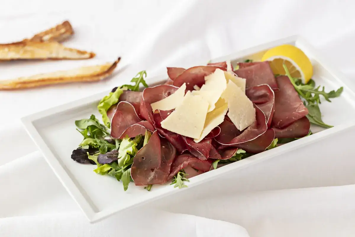 Bresaola con scaglie di formaggio, un abbinamento perfetto per un antipasto leggero e gustoso.