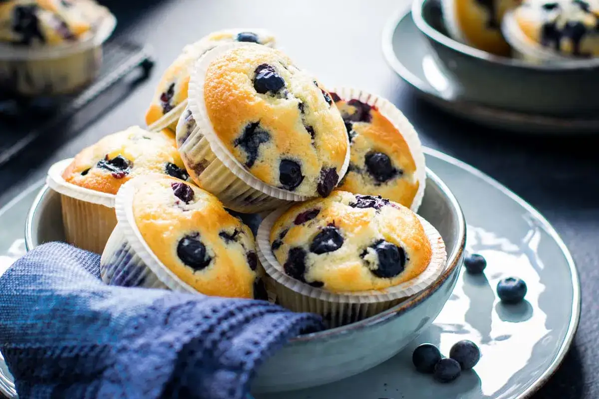 Muffin ai mirtilli appena sfornati, dorati e soffici, pronti per essere gustati. Una deliziosa ricetta per la colazione o la merenda.