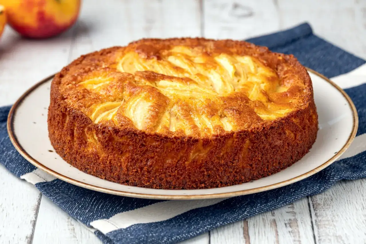 Torta margherita con mele dorata e profumata, con mele a vista sulla superficie.