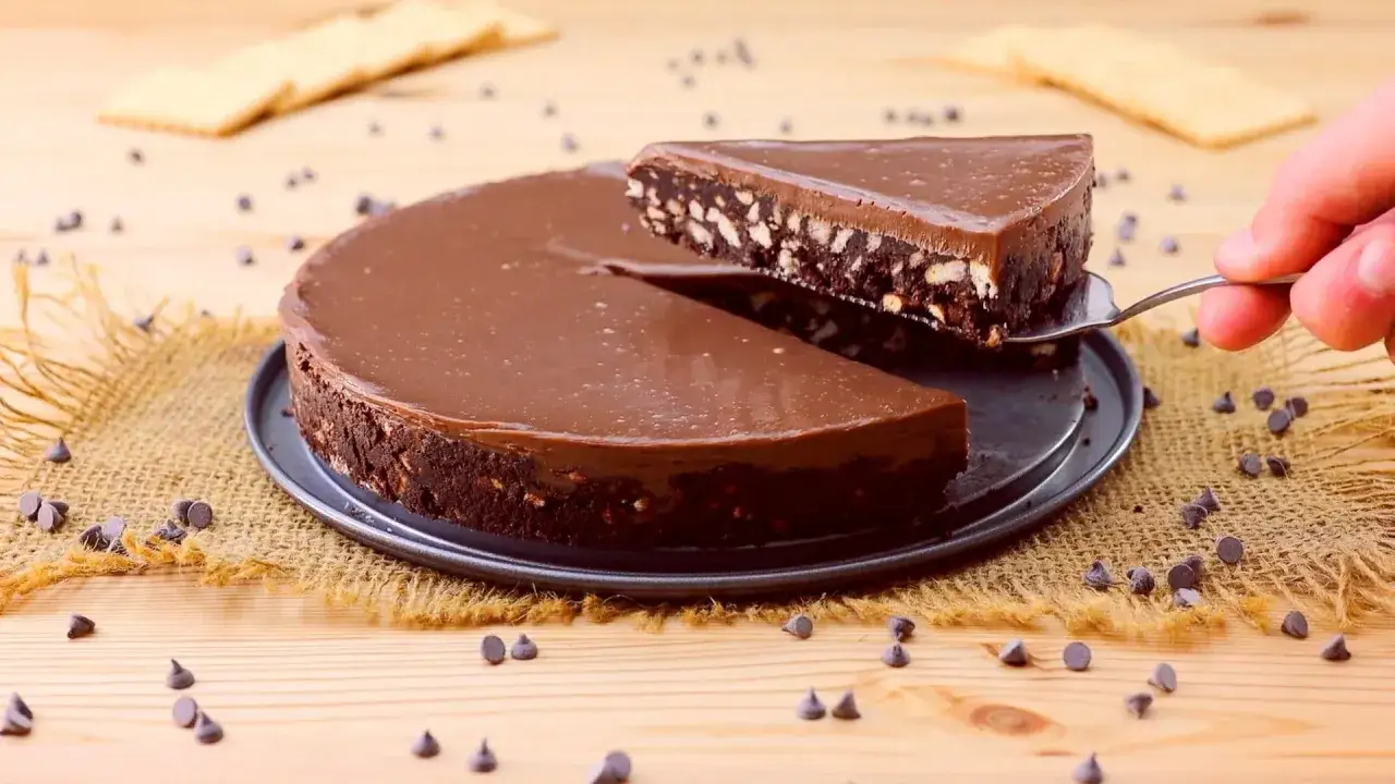 Torta al cioccolato con biscotti, perfetta per dolci veloci senza uova e senza cottura. Una fetta viene sollevata con una paletta.