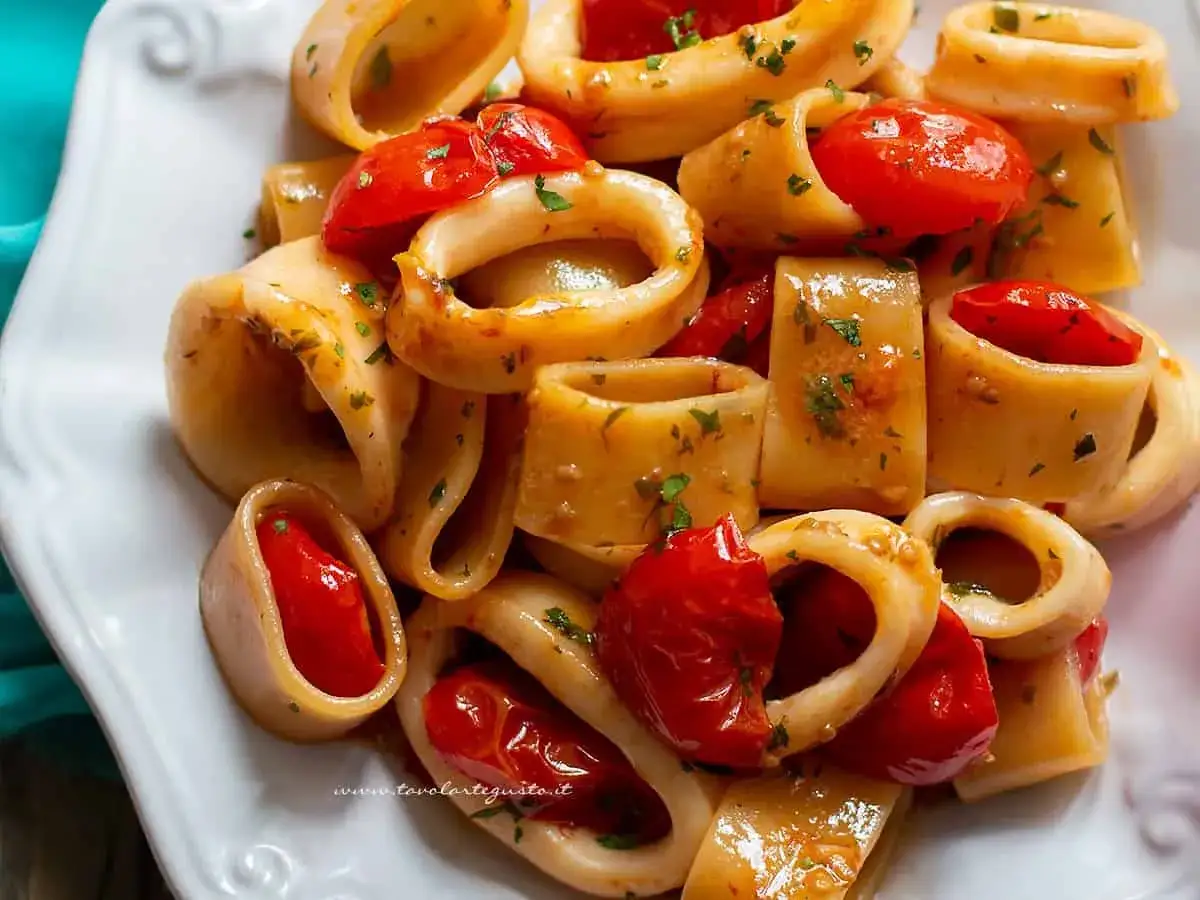 Un piatto invitante di calamarata con pomodorini freschi e prezzemolo tritato. Una ricetta semplice e gustosa.