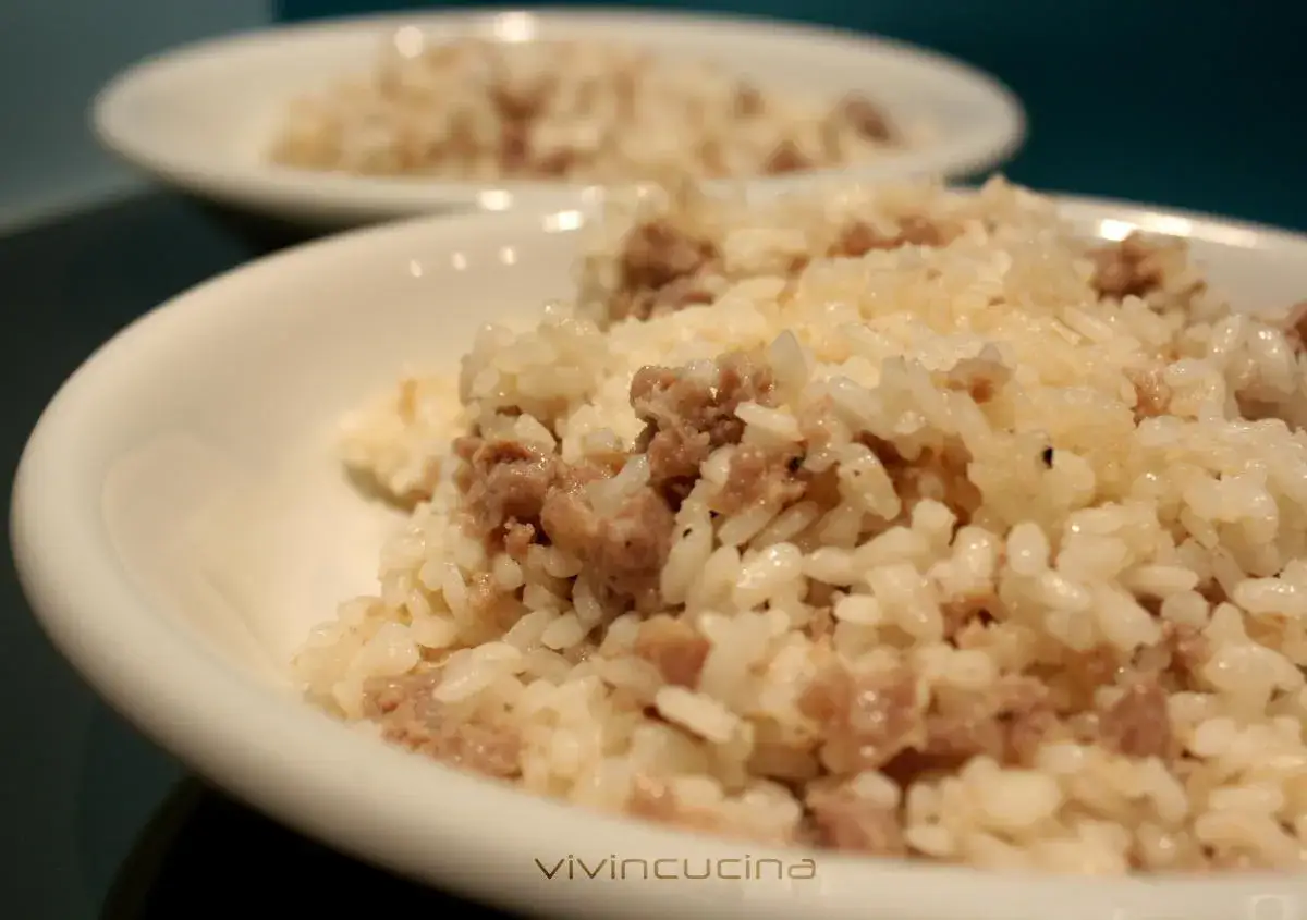 Risotto alla mantovana ingredienti: riso cremoso con salsiccia sbriciolata, servito in ciotole bianche.