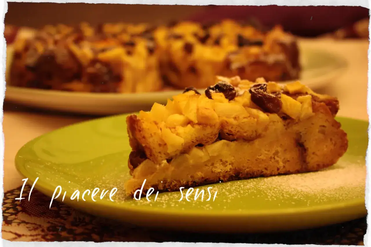 Una fetta di torta con pandoro avanzato e mele, cosparsa di zucchero a velo, su un piatto verde. Un piacere per i sensi.