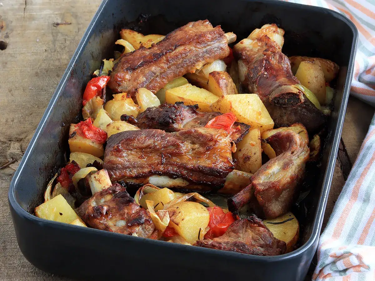 Rosticciana al forno morbida con patate, cipolle e peperoni, un piatto succulento e profumato.