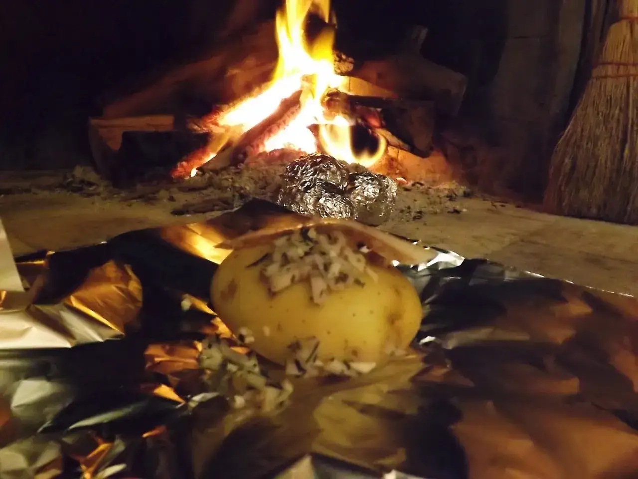 Patate alla brace, condite con erbe aromatiche, cuociono lentamente vicino al fuoco scoppiettante.