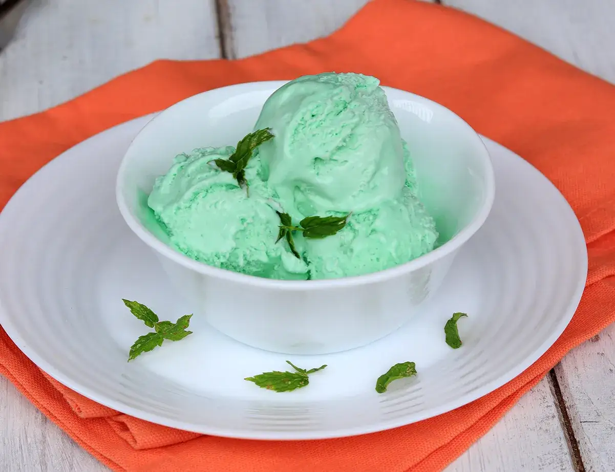 Coppette di gelato alla menta con latte condensato, guarnite con foglie di menta fresca.