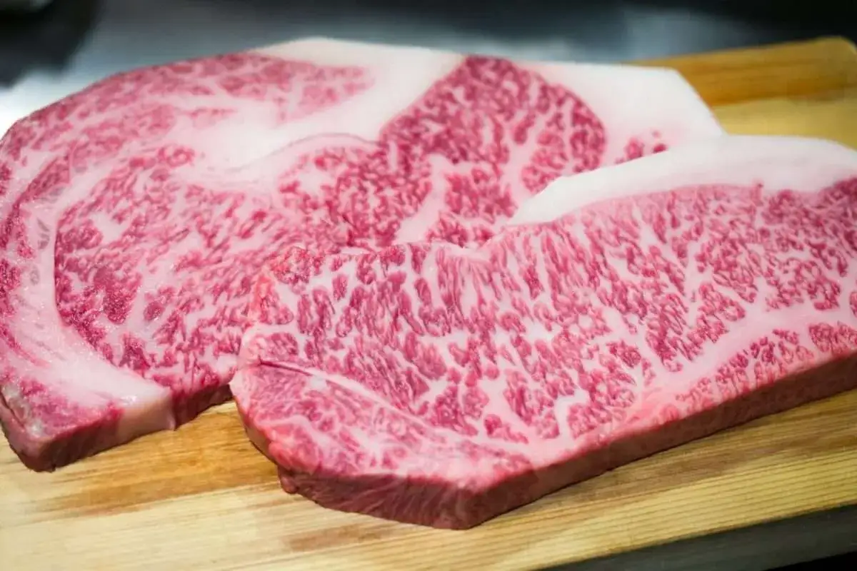Due bistecche di pregiata mucca Kobe, con la loro caratteristica marezzatura rosata e bianca, pronte per essere cucinate.