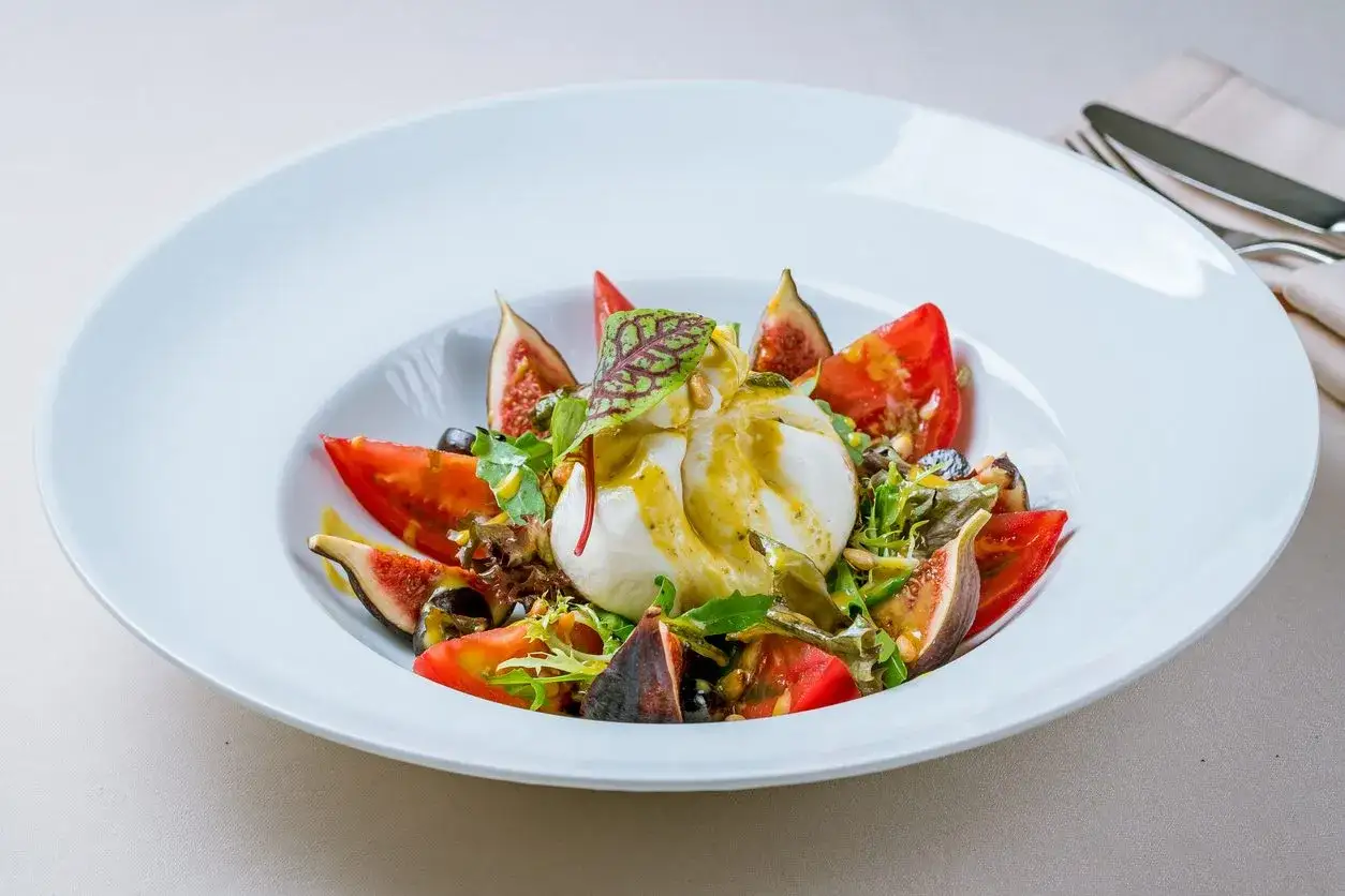 Burrata affumicata con fichi, pomodori e rucola. Un piatto fresco e gustoso, perfetto per scoprire nuovi abbinamenti.