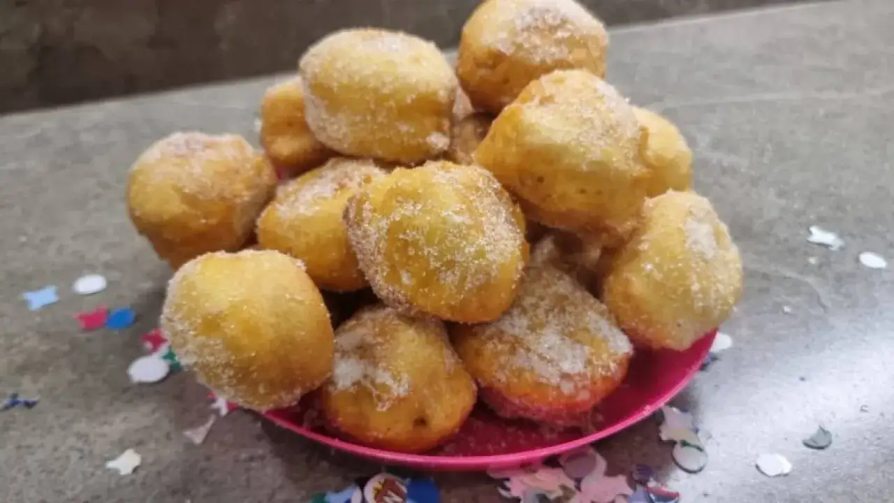 Frittelle dolci in padella, dorate e cosparse di zucchero, pronte per essere gustate. Un'esplosione di sapore!