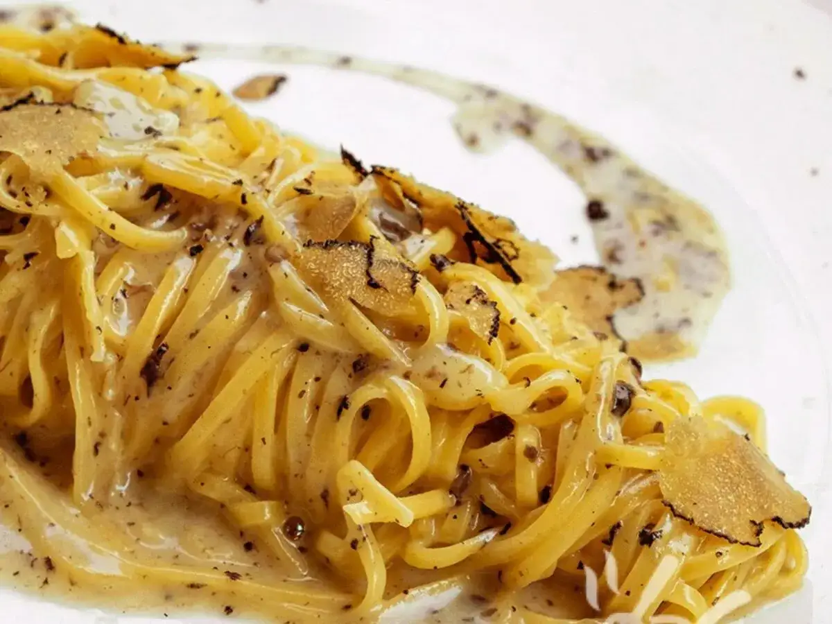 Un piatto di linguine cremose, condite con scaglie di tartufo nero e bianco. Un'esperienza di puro piacere per il palato, un'autentica pasta al tartufo.