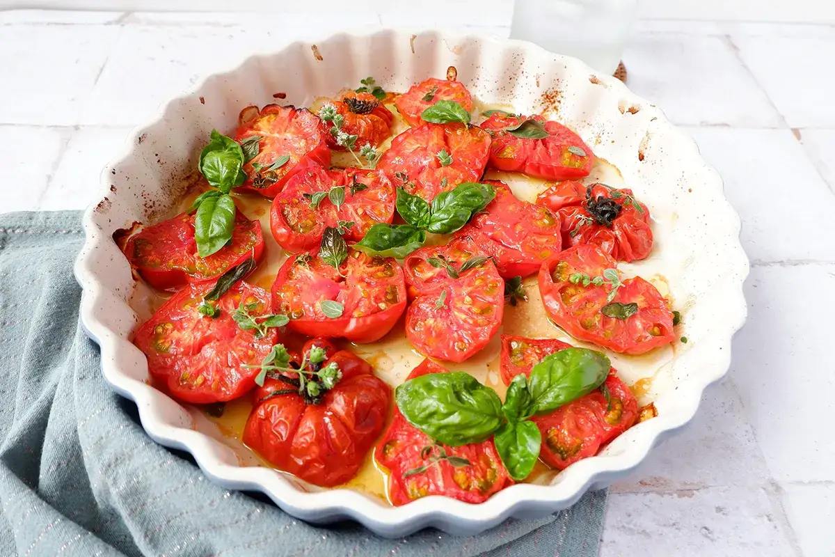 Pomodori al forno succosi e profumati, guarniti con basilico fresco e origano. Un contorno semplice e delizioso.