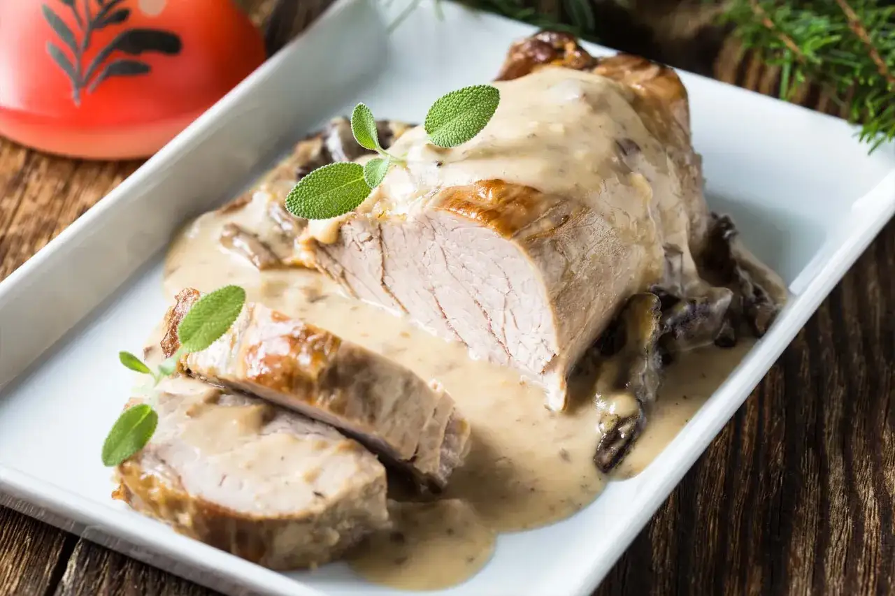 Arista al latte succulenta, affettata e ricoperta da una cremosa salsa ai funghi, guarnita con foglie di salvia fresca.
