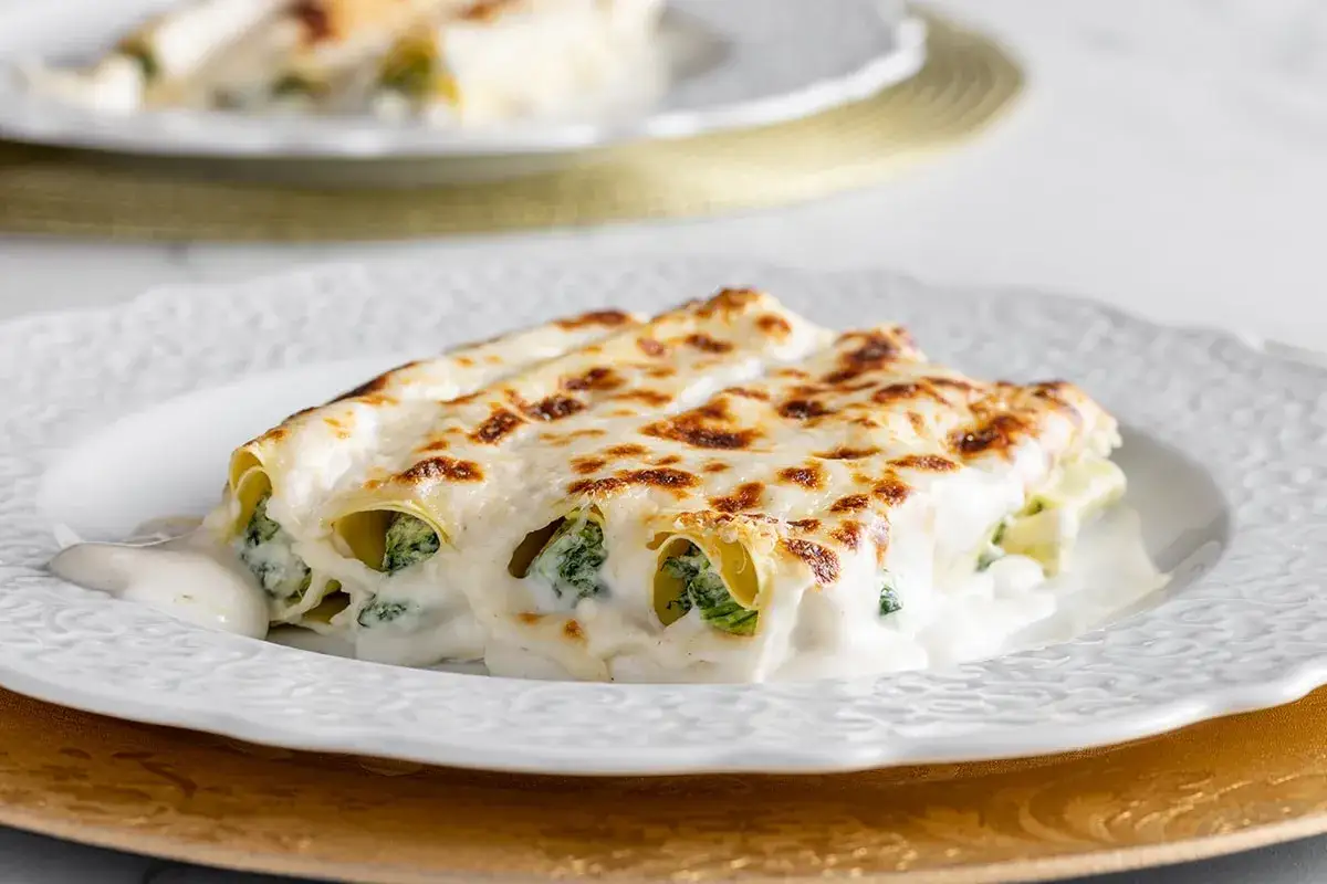 Cannelloni ricotta e spinaci dorati al forno, ricoperti da besciamella cremosa e formaggio fuso.