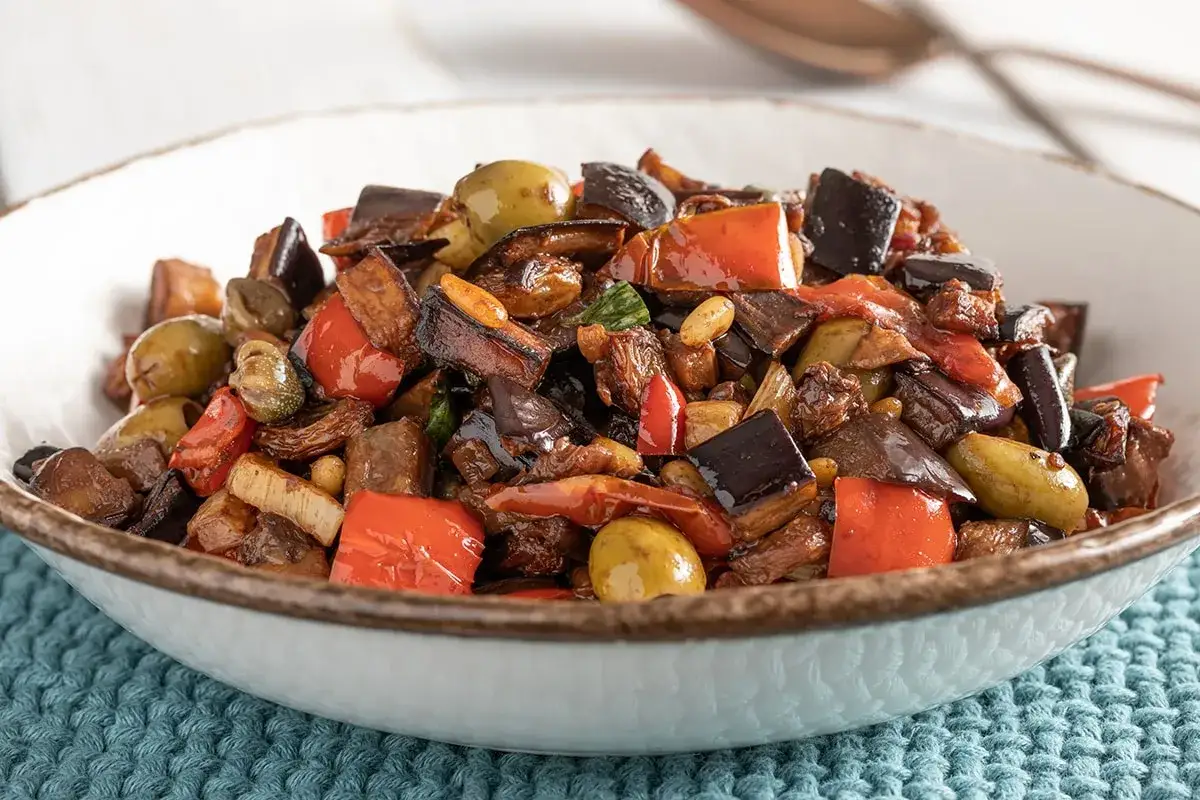 Caponata ricetta: un piatto ricco di melanzane, peperoni, olive e capperi, pronto per essere gustato.