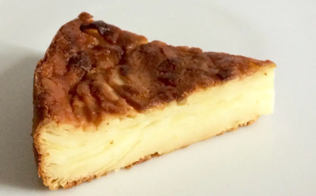 Una fetta di torta di mele fondente con strati dorati e una crosta caramellata.