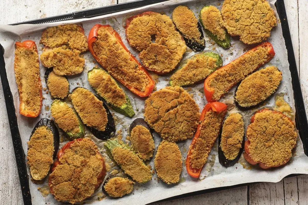 Verdure al forno dorate e croccanti: peperoni, melanzane e zucchine ripiene di pangrattato e erbe aromatiche, pronte per essere gustate.