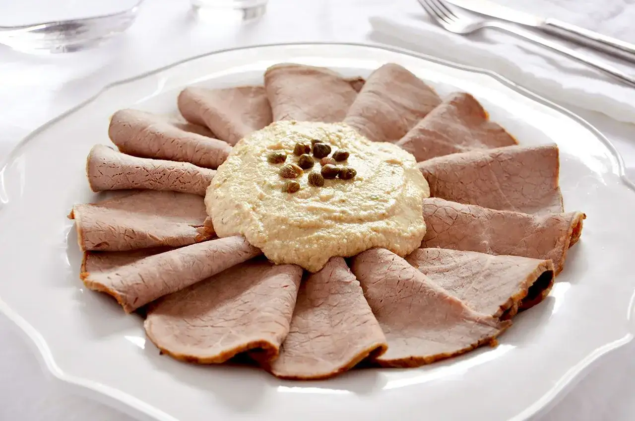 Vitello tonnato ricetta originale piemontese: fettine di arrosto di vitello disposte a raggiera attorno a una salsa cremosa con capperi.