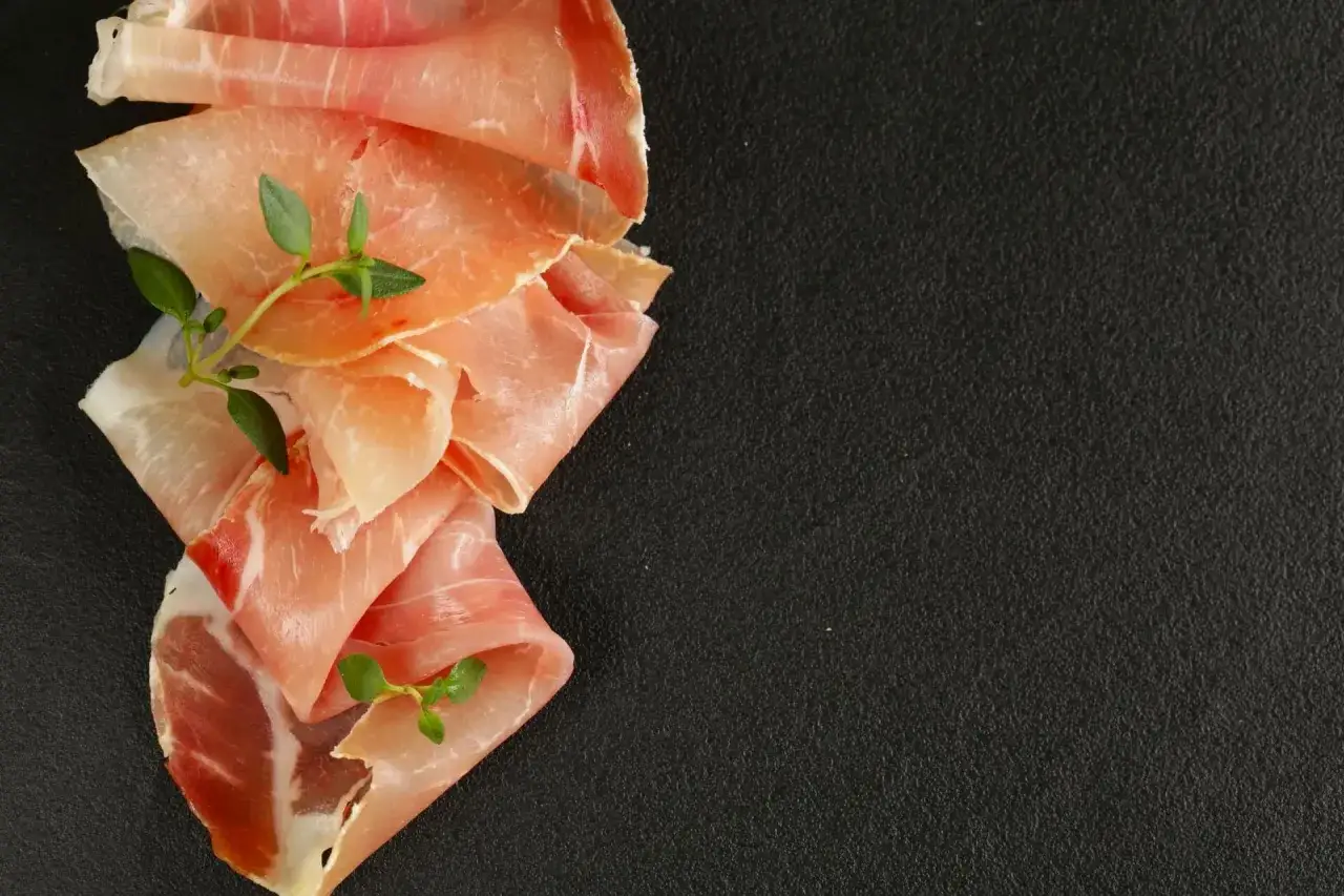 Fettine di prosciutto crudo e speck, con rametti di timo, per mostrare la differenza tra speck e prosciutto crudo.