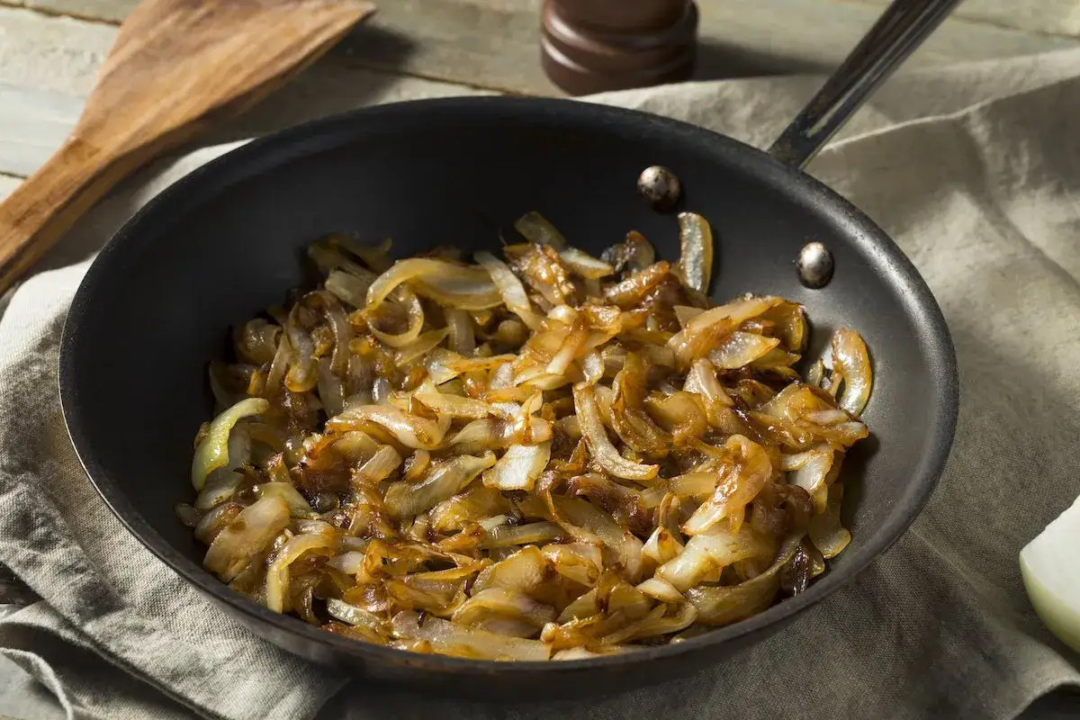 Cipolle caramellate dorate e succulente in padella, pronte per arricchire ogni piatto.