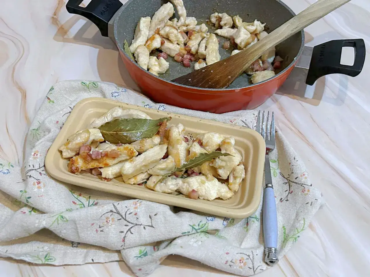 Bocconcini di pollo con pancetta, cotti in padella e serviti su un piatto, con foglie d'alloro.