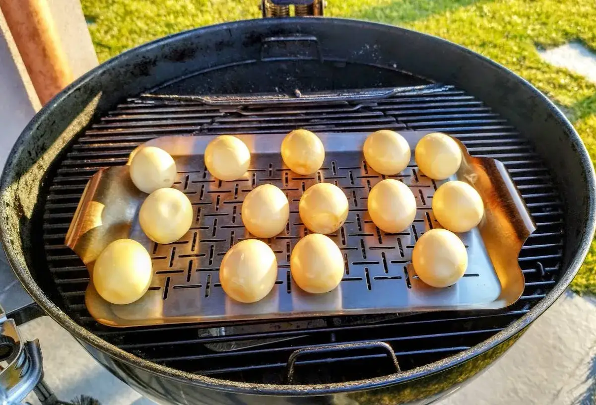 Dodici uova alla griglia su una teglia metallica, pronte per essere cucinate all'aperto.