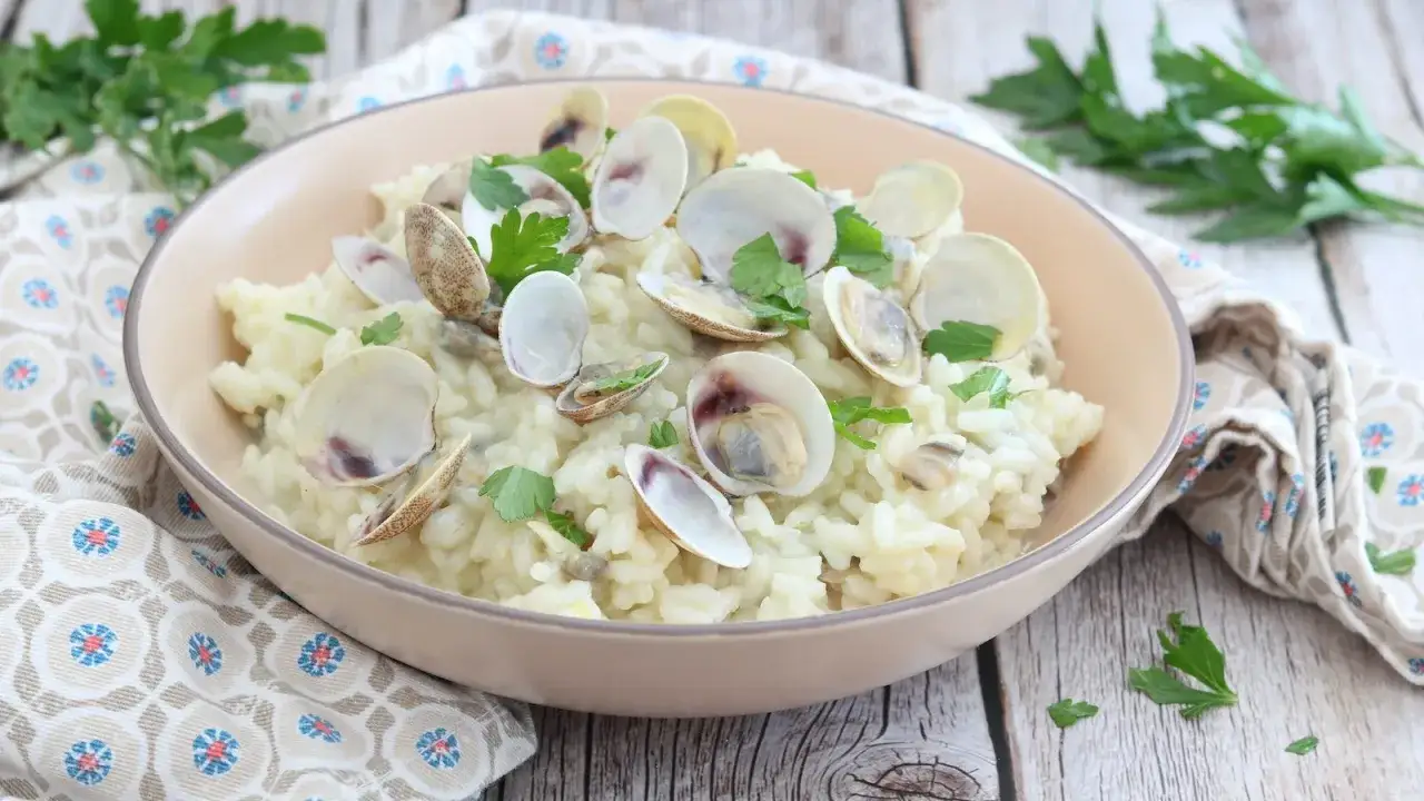 Un cremoso risotto alle vongole, guarnito con prezzemolo fresco, pronto per essere gustato.
