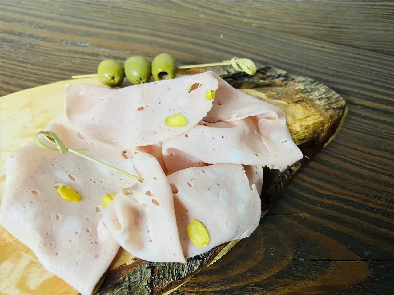 Fette di mortadella con pistacchi e olive verdi, un assaggio di come si fa la mortadella.