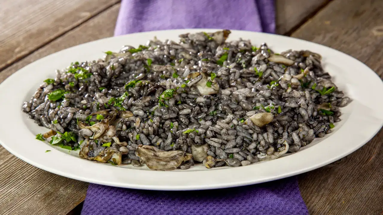 Un invitante risotto al nero di seppia, guarnito con prezzemolo fresco, servito su un piatto bianco.