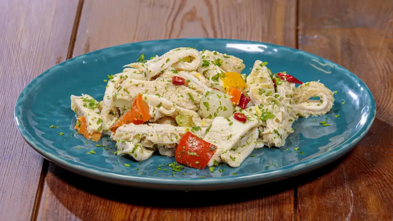 Un piatto invitante di insalata di trippa, condita con erbe fresche, peperoncino e verdure colorate.