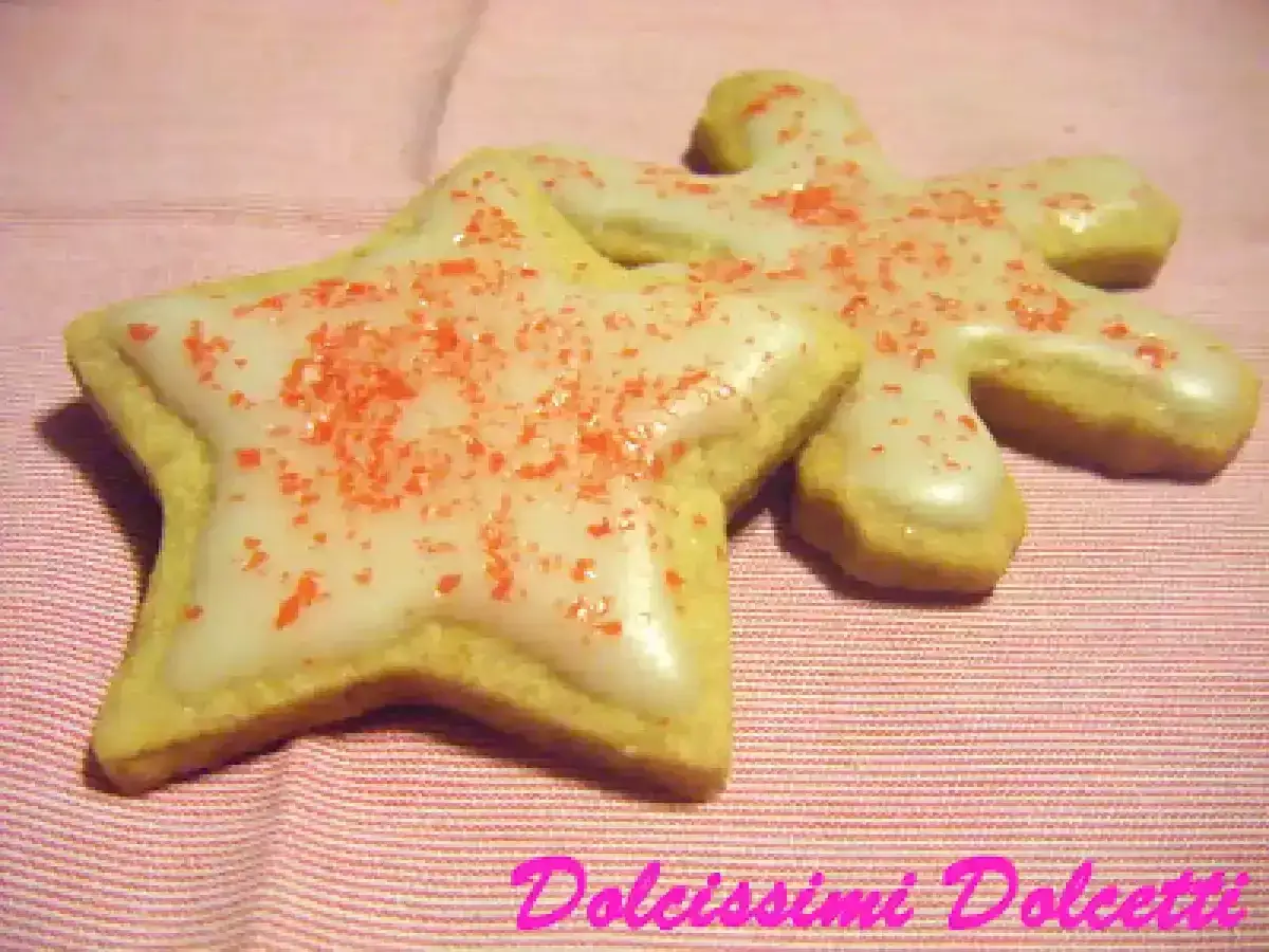 Biscotti a forma di stella e omino, ricoperti da glassa con zucchero a velo e acqua, spolverati con granella rossa.