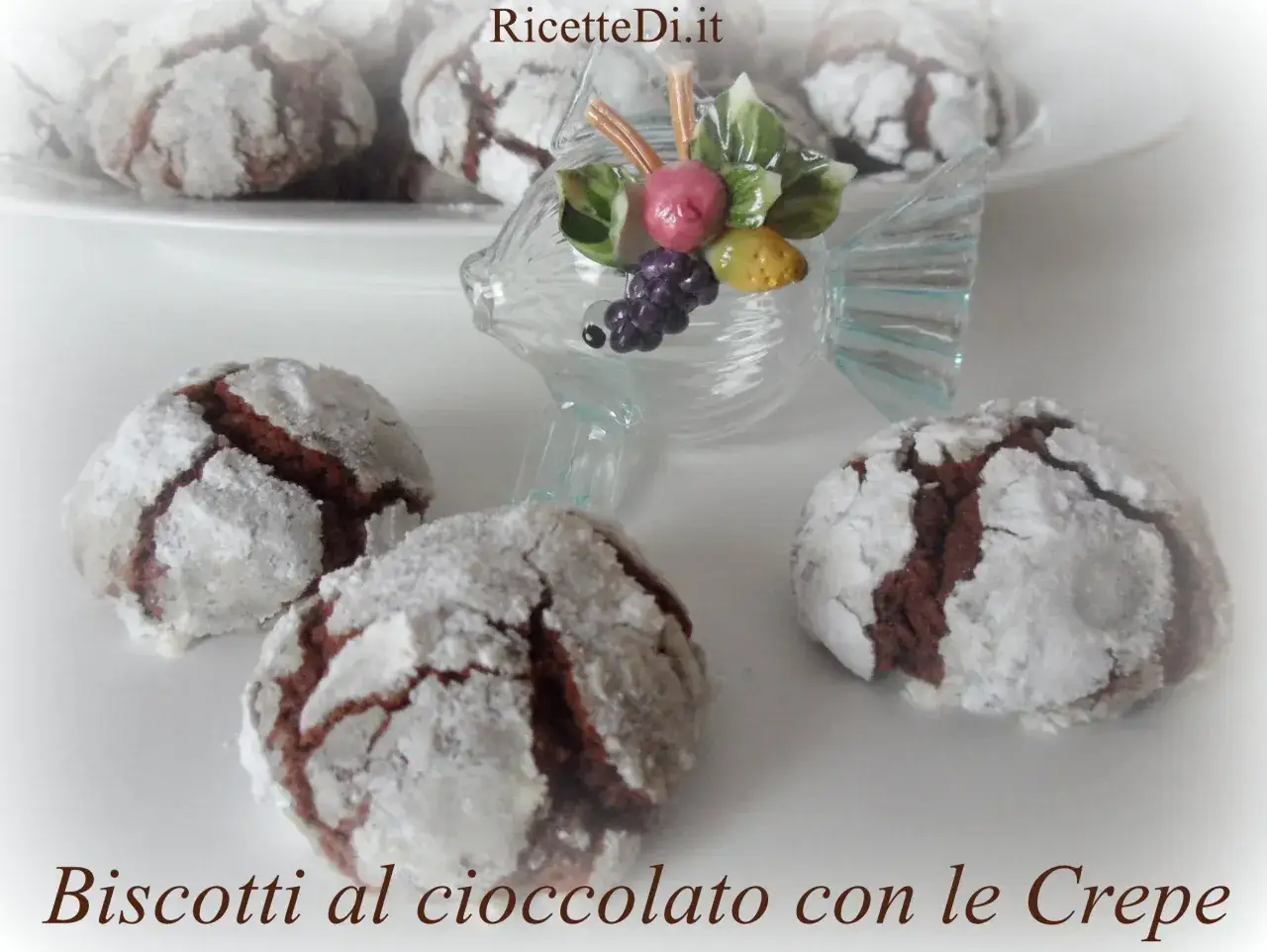 Biscotti al cioccolato con le crepe, crinkles cookies ricoperti di zucchero a velo, con una decorazione a forma di pesce in vetro.
